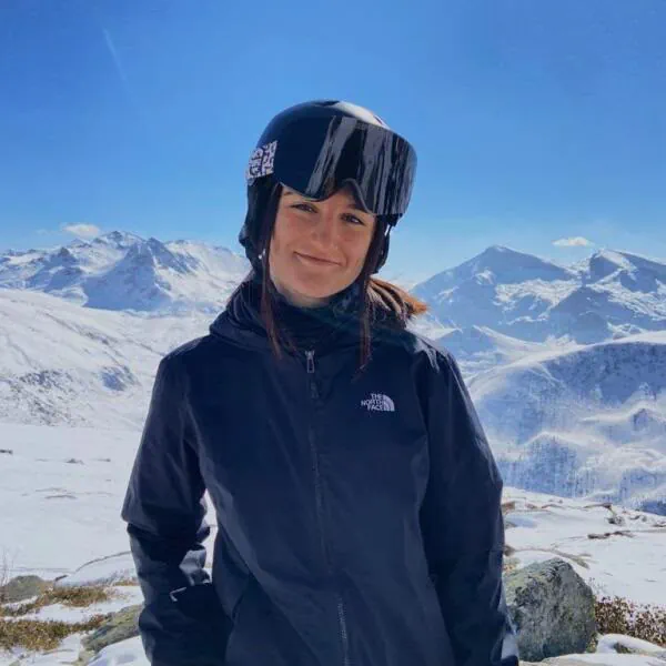 Valentina at the top, helmet and goggles on, mountains behind